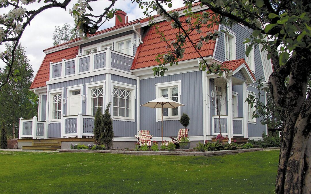 Puuverhoiltu siniharmaa talo, jossa on punainen tiilikatto.