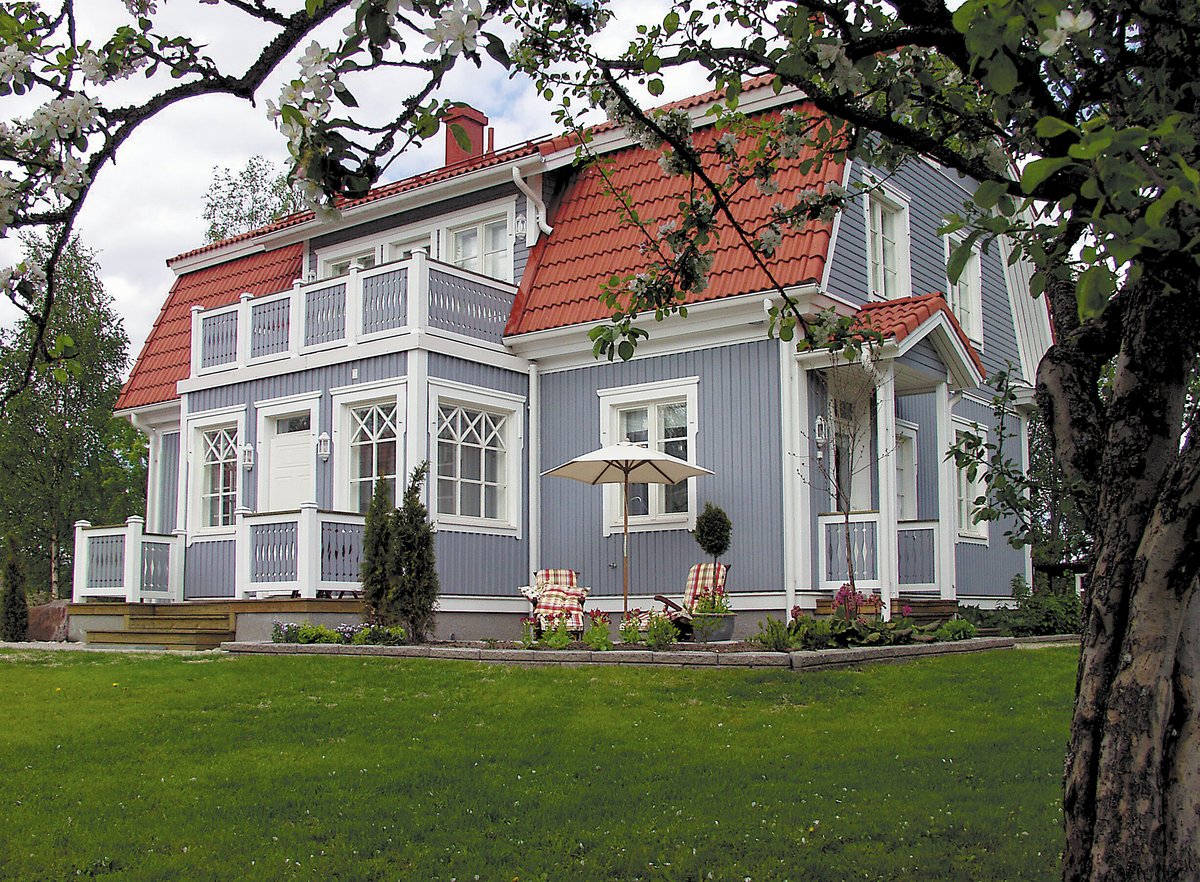 Puuverhoiltu siniharmaa talo, jossa on punainen tiilikatto.